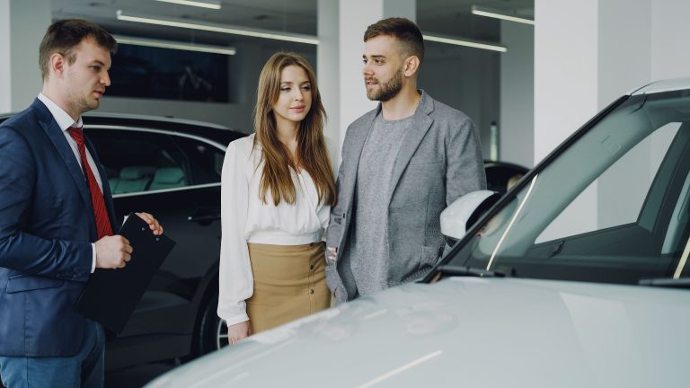 Couple discutant avec vendeur automobile concessionnaire