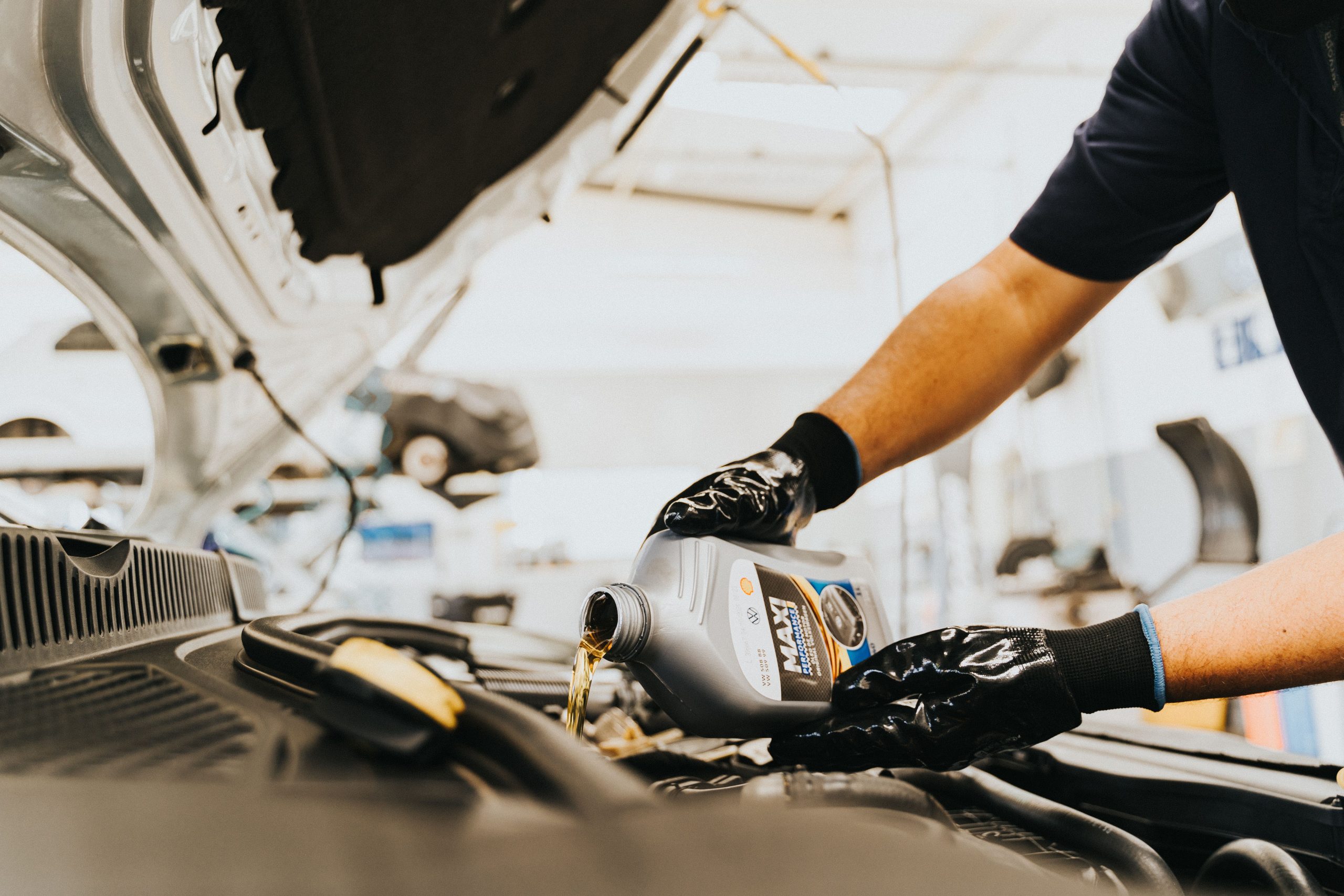 Mécanicien en gants versant huile dans garage
