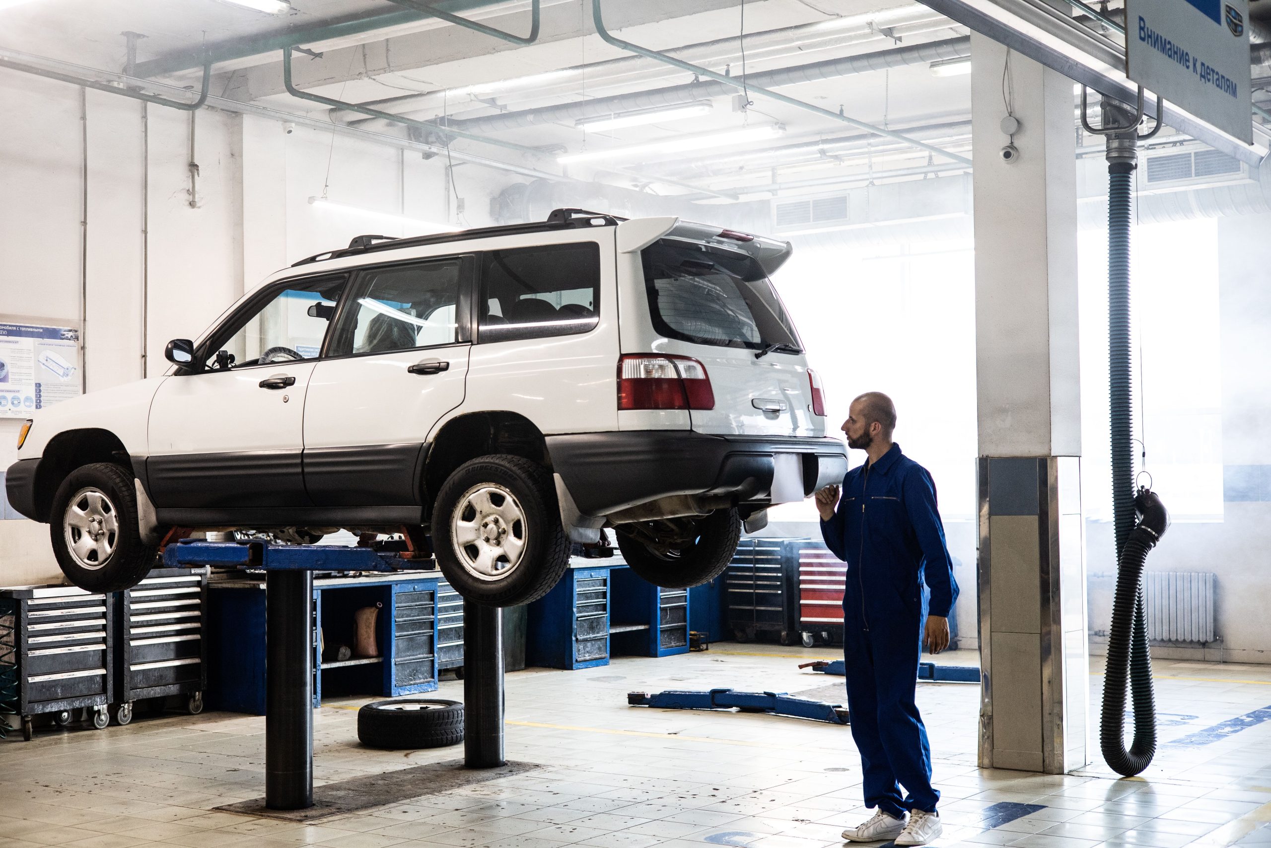 Mécanicien inspectant véhicule levé garage