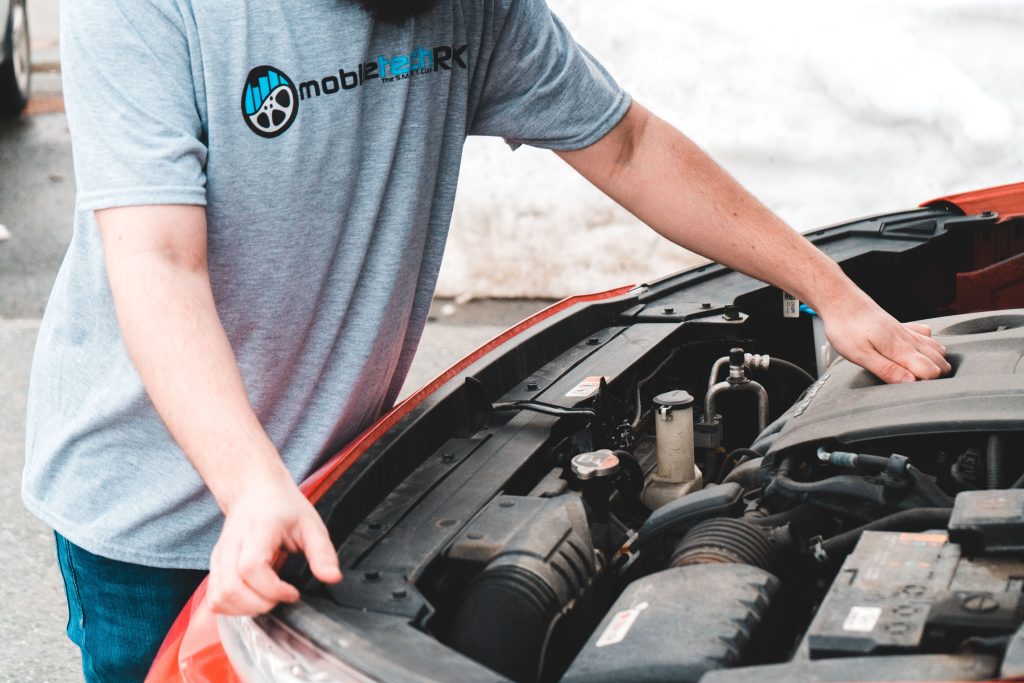 Homme inspectant le moteur d'une voiture