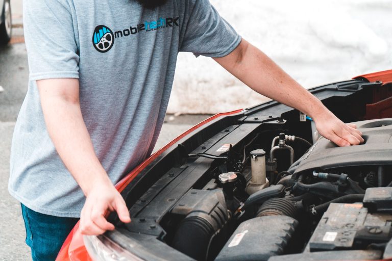 Homme inspectant le moteur d'une voiture