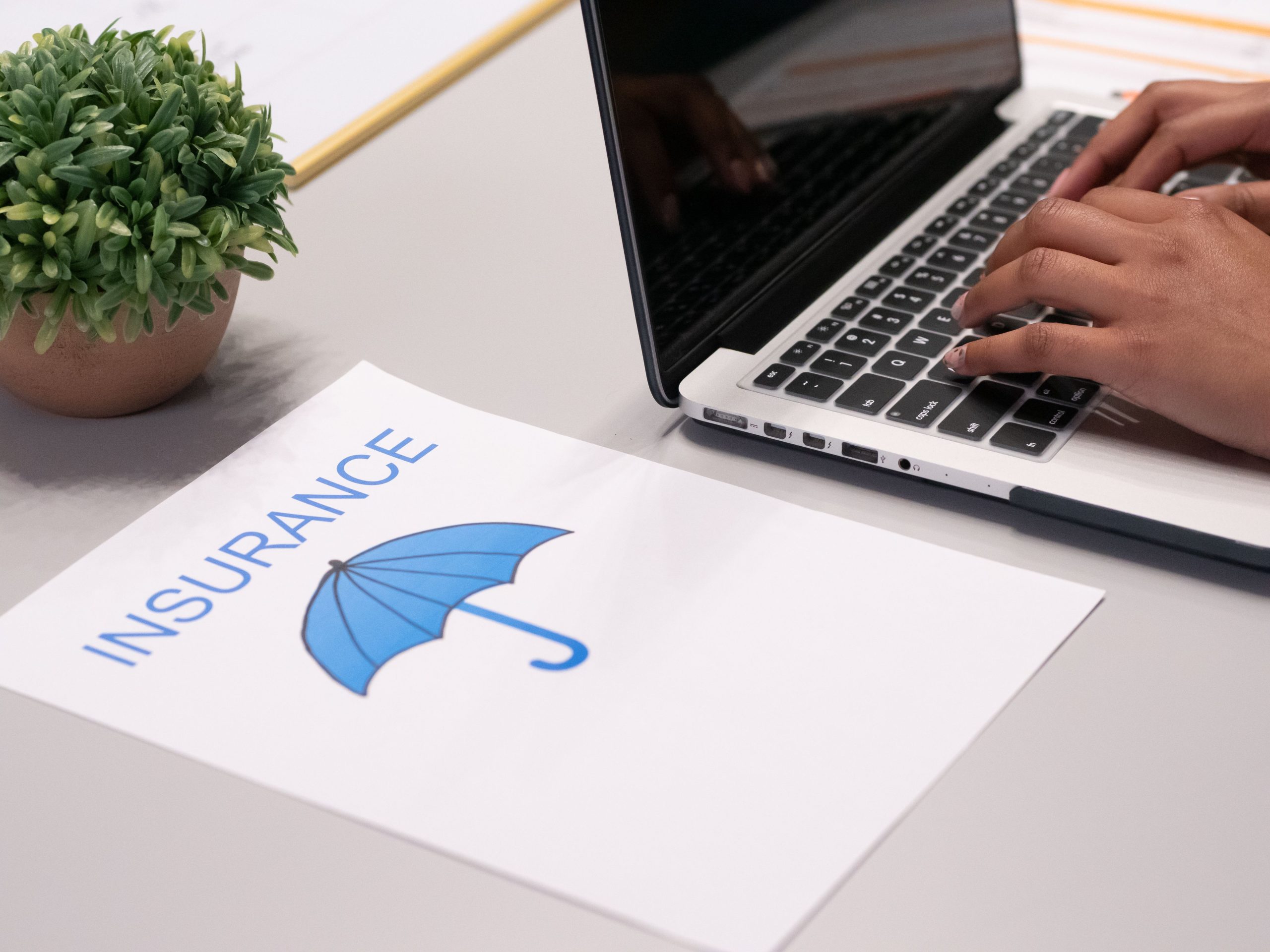 Mains tapant sur ordinateur avec document assurance
